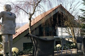 En staty av en kvinna med ett halsband, en byggnad med ett sluttande tak och flätade stolar.