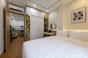 A modern bedroom with a large bed, a desk with a laptop, a mirror, and a bookshelf. - Westlake House by Jen (Hanoi)