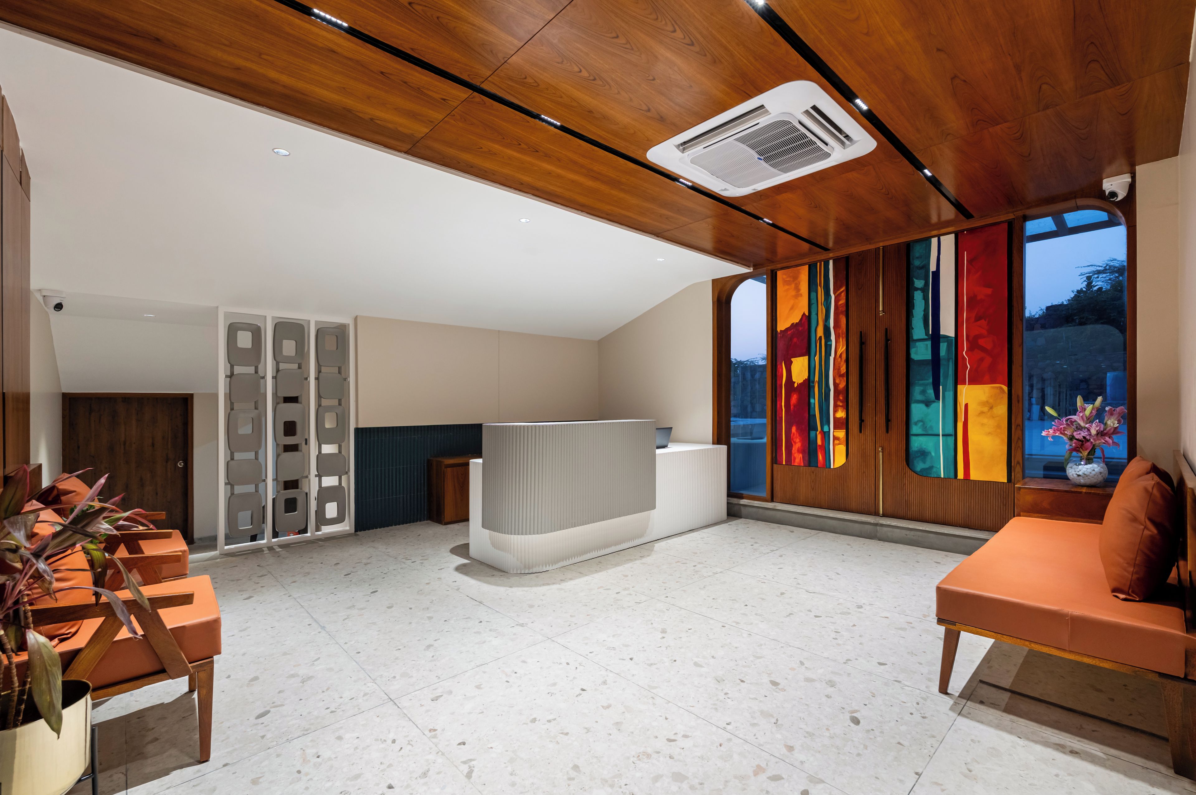 A modern reception area with a wooden ceiling, a reception desk, and a large window with a colorful view.