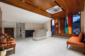 A modern reception area with a wooden ceiling, a reception desk, and a large window with a colorful view. - Traavista Rivera The Lake House (Udaipur)