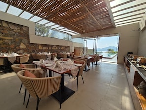 Un ristorante con posti a sedere all'aperto, pareti in pietra e vista sulle montagne.