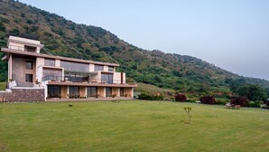 A modern two-story building with a flat roof, large windows, and a stone facade. - Traavista Rivera The Lake House (Panwari)