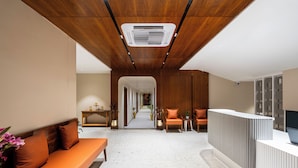 A modern lobby with a wooden ceiling, a reception desk, seating area, and a hallway leading to other rooms. - Traavista Rivera The Lake House (Panwari)