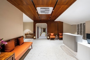 Una hall moderna con soffitto in legno, una reception, un'area salotto e un corridoio che porta ad altre stanze.