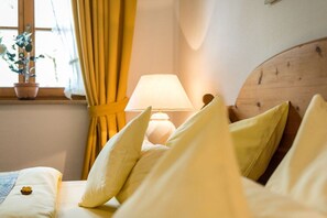 A bed with pillows, a bedside lamp, a window with curtains, and a potted plant. - Haus Sprenzel - Bettina Holiday Apartment (Garmisch-Partenkirchen)