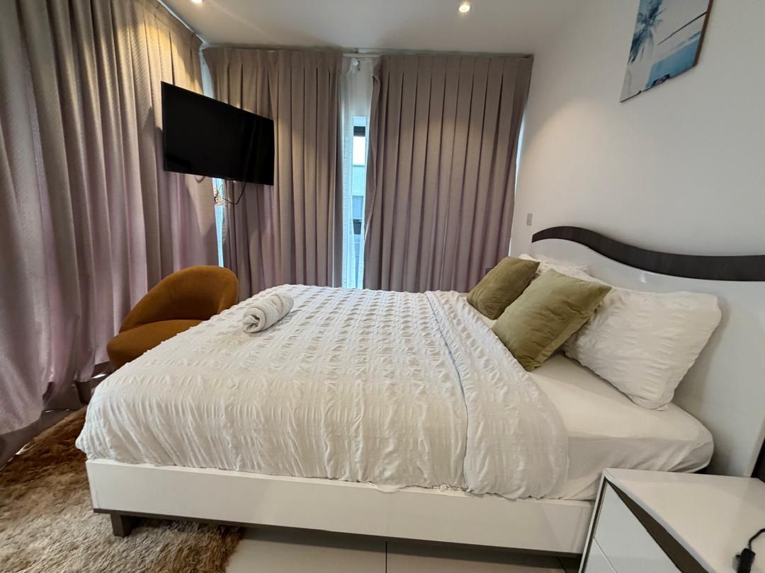 Una habitación de hotel con una cama, un televisor montado en la pared y una silla.