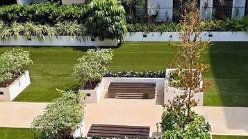 A landscaped courtyard with a central seating area, surrounded by planters and grass.