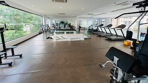 Un gimnasio moderno con cintas de correr, máquinas de pesas y bancos.