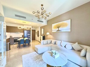 A modern living room with a sectional sofa, a round coffee table, and a dining area with chairs. - Charming 2-bedroom apartment with AC in delightful Dubai (Dubai)