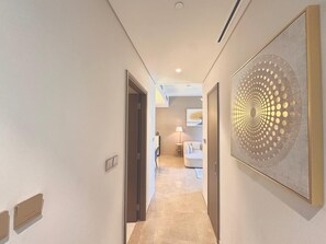 A hallway with a modern art piece on the right, a door on the left, and a living area in the distance. - Charming 2-bedroom apartment with AC in delightful Dubai (Dubai)