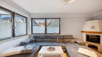Un salon moderne avec un canapé d’angle, une table basse blanche et une cheminée.