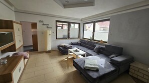 En moderne stue med en grå hjørnesofa, et lille hvidt bord og et træskab.