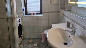 A bathroom with a glass shower enclosure, a built-in sink, and a window with blinds. - Apartment 'HarzNest' with Private Terrace, Private Garden and Wi-Fi (Wimmelburg)