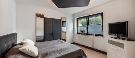 Ein modernes Schlafzimmer mit einem Bett, einem Fernseher und einem Fenster mit Jalousien.