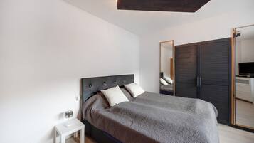 Un dormitorio moderno con cama, mesita de noche y espejo.