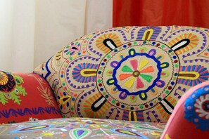 A colorful, intricately patterned cushion with a circular design, placed on a bed with a multicolored, patterned bedspread. - Holiday apartment with 1 bedroom (Lindau)