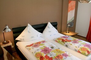 A hotel room with a bed, pillows, a nightstand, a lamp, and a wall painting. - Holiday apartment with 1 bedroom (Lindau)