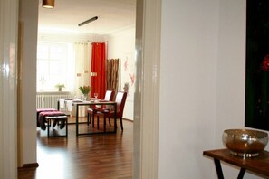 A dining area with a table and chairs, a red curtain, and a window with natural light. - Holiday apartment with 1 bedroom (Lindau)