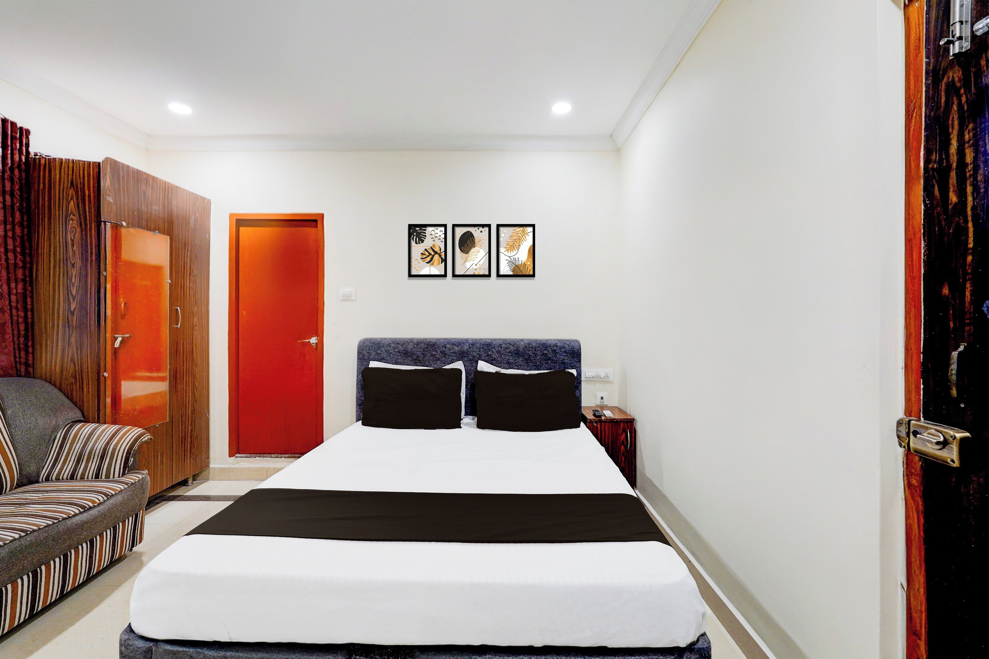 Una habitación de hotel con cama, una silla, un armario y una puerta.