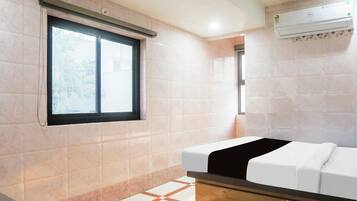 Un baño con ventana, ducha y cama.