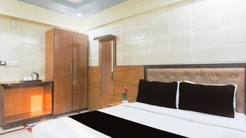 Una habitación de hotel con cama, armario de madera, mesita de noche y espejo.
