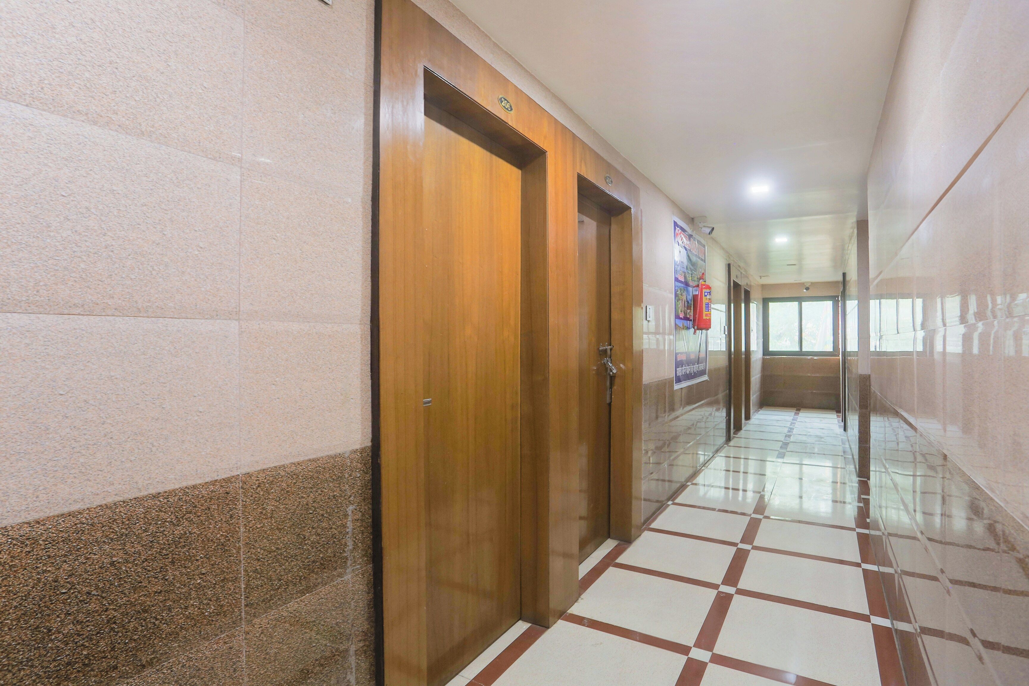 A corridor with wooden doors, tiled flooring, and a fire extinguisher on the wall.