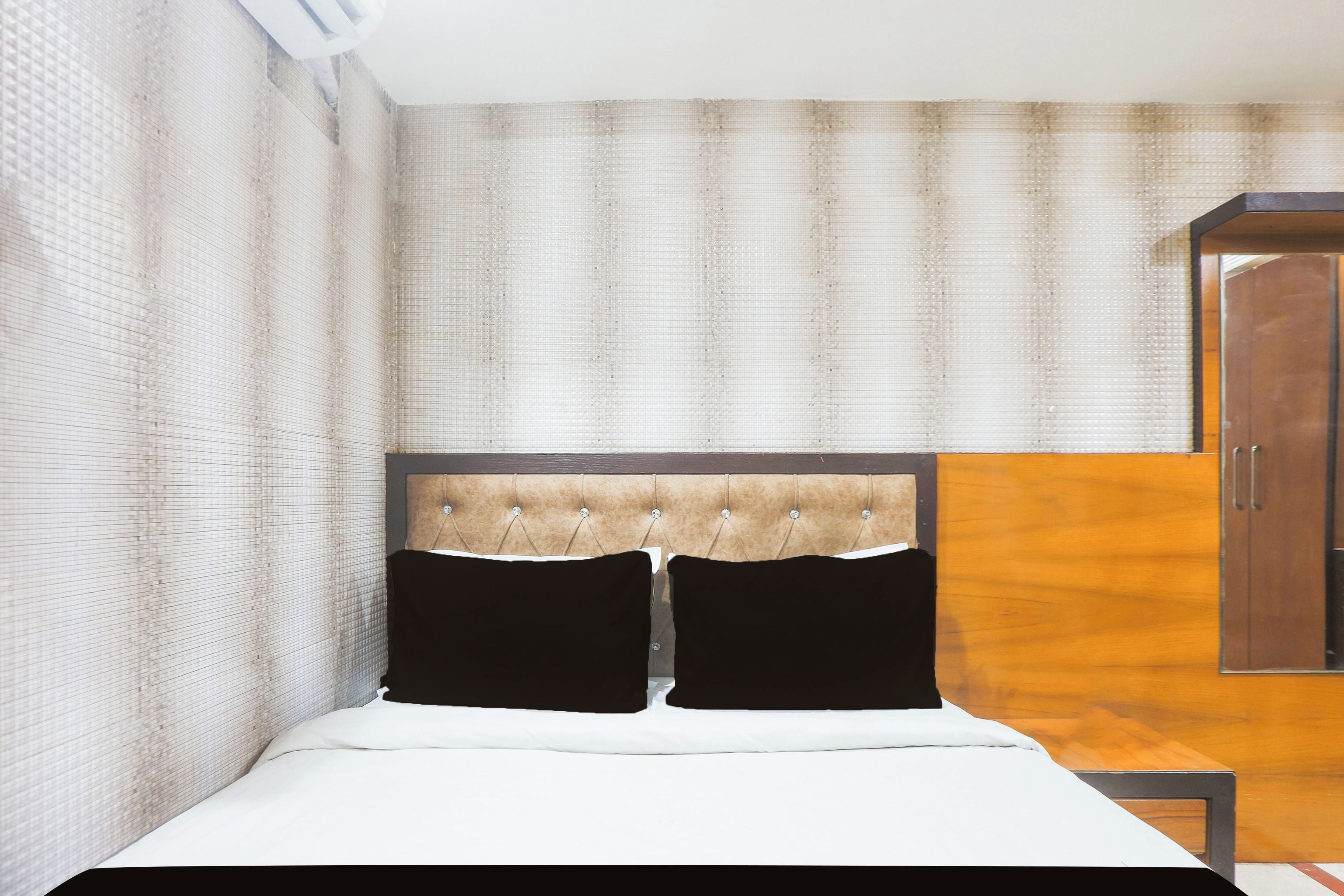 A bedroom with a bed, a wooden wardrobe, and a headboard with a tufted design.