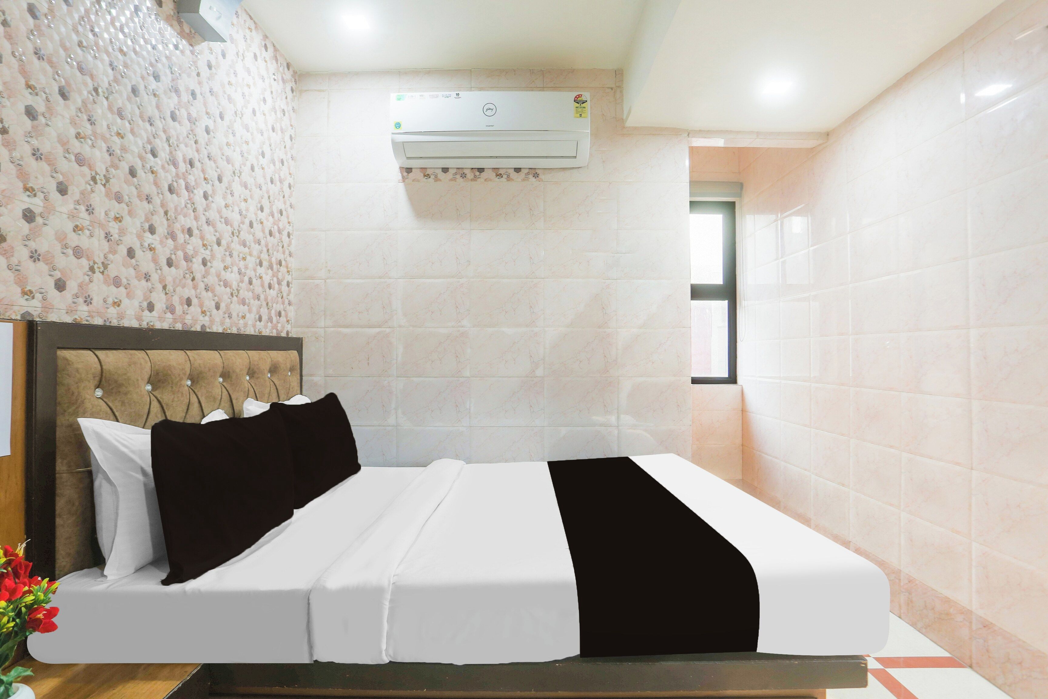 Une chambre d’hôtel avec un lit, une tête de lit, un climatiseur fixé au mur et une fenêtre.