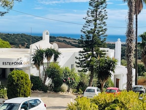 Ein weißes Gebäude mit einem Schild, auf dem 'ESTEPONA GOLF' steht, und im Hintergrund Meerblick.