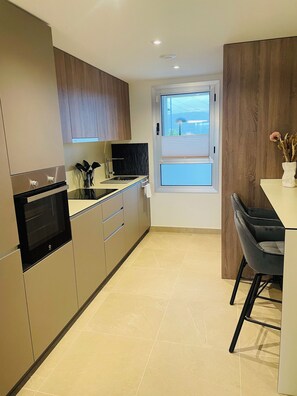 Una cucina moderna con elettrodomestici integrati, una finestra vista e un'area pranzo con una sedia.
