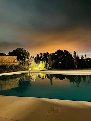 Ein Swimmingpool mit klarer Spiegelung, ein Stoppschild und Bäume im Hintergrund.
