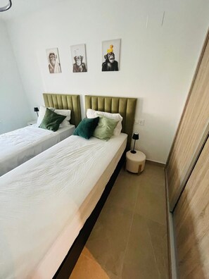 Ein Hotelzimmer mit zwei Betten, einem Nachttisch, einer Lampe und drei Bildern an der Wand.