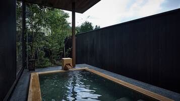 A rectangular pool with a wooden edge, surrounded by a dark fence, and a small wooden stool near the water's edge.