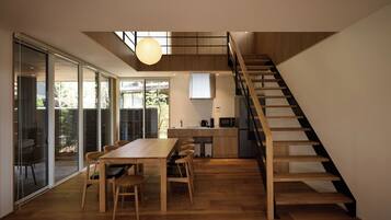 Un interior moderno con comedor, cocina y una escalera de madera.
