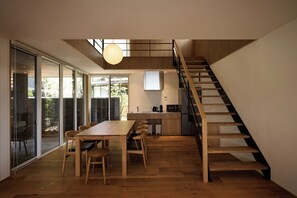 Un interior moderno con comedor, cocina y una escalera de madera.