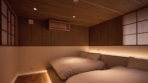 A bedroom with two beds, wooden flooring, and a sloped ceiling with recessed lighting. - tuuli YUFU Kinrinko (Yufu)
