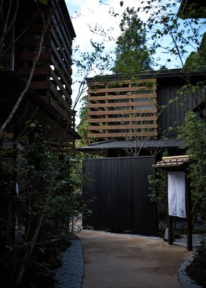 A pathway leading to a building with a wooden facade and a black fence. - tuuli YUFU Kinrinko (Yufu)