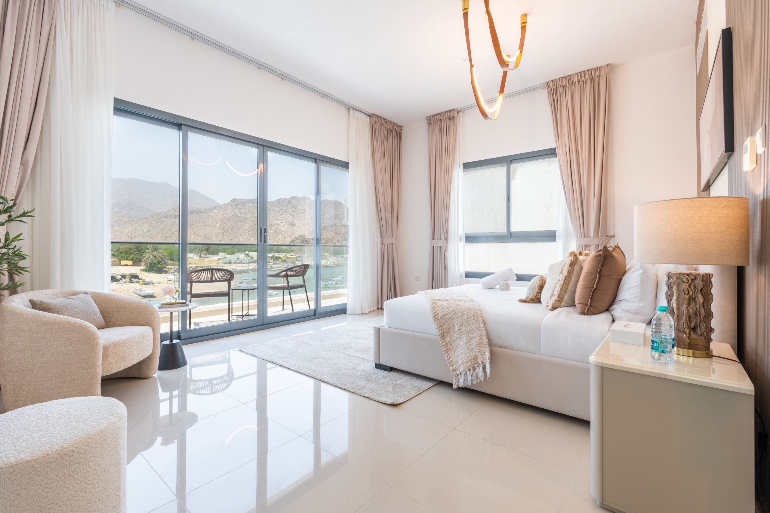 Ein modernes Hotelzimmer mit einem großen Balkon, einem Sofa, einem Bett und einem Nachttisch.
