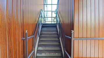 A wooden staircase with metal railings leading to a bright interior space.