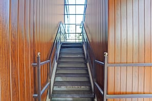 Una escalera de madera con barandillas de metal que conduce a un espacio interior luminoso.