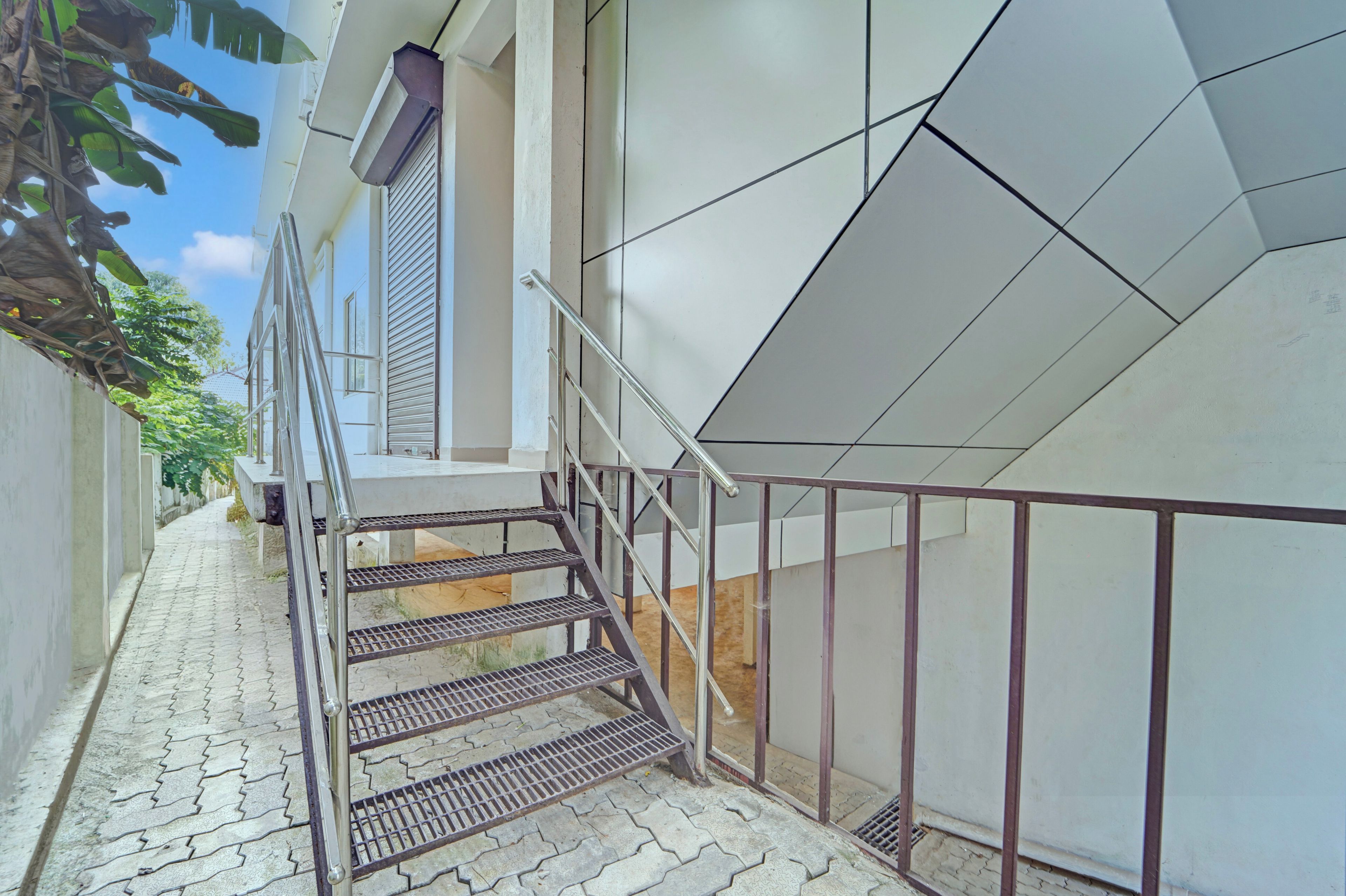 Una escalera con barandillas metálicas que conduce a un edificio de fachada geométrica.