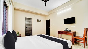 A hotel room with a bed, a desk, a chair, a television, and a door.