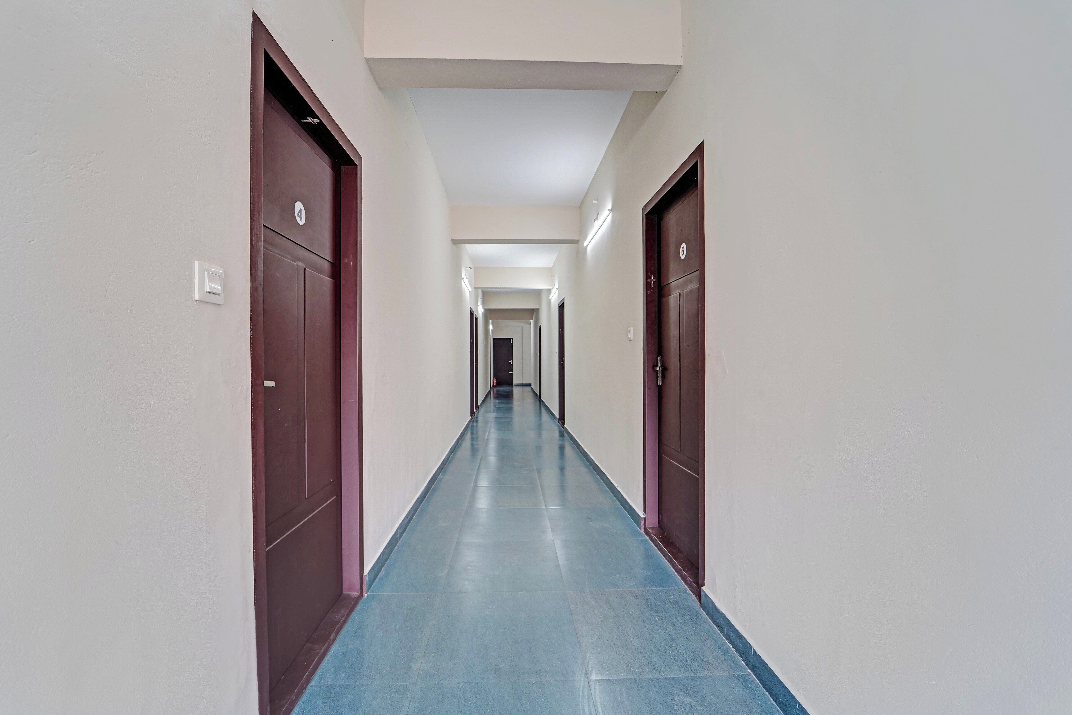 Un pasillo largo y estrecho con puertas a ambos lados, con los números 4 y 6, que conduce a habitaciones.