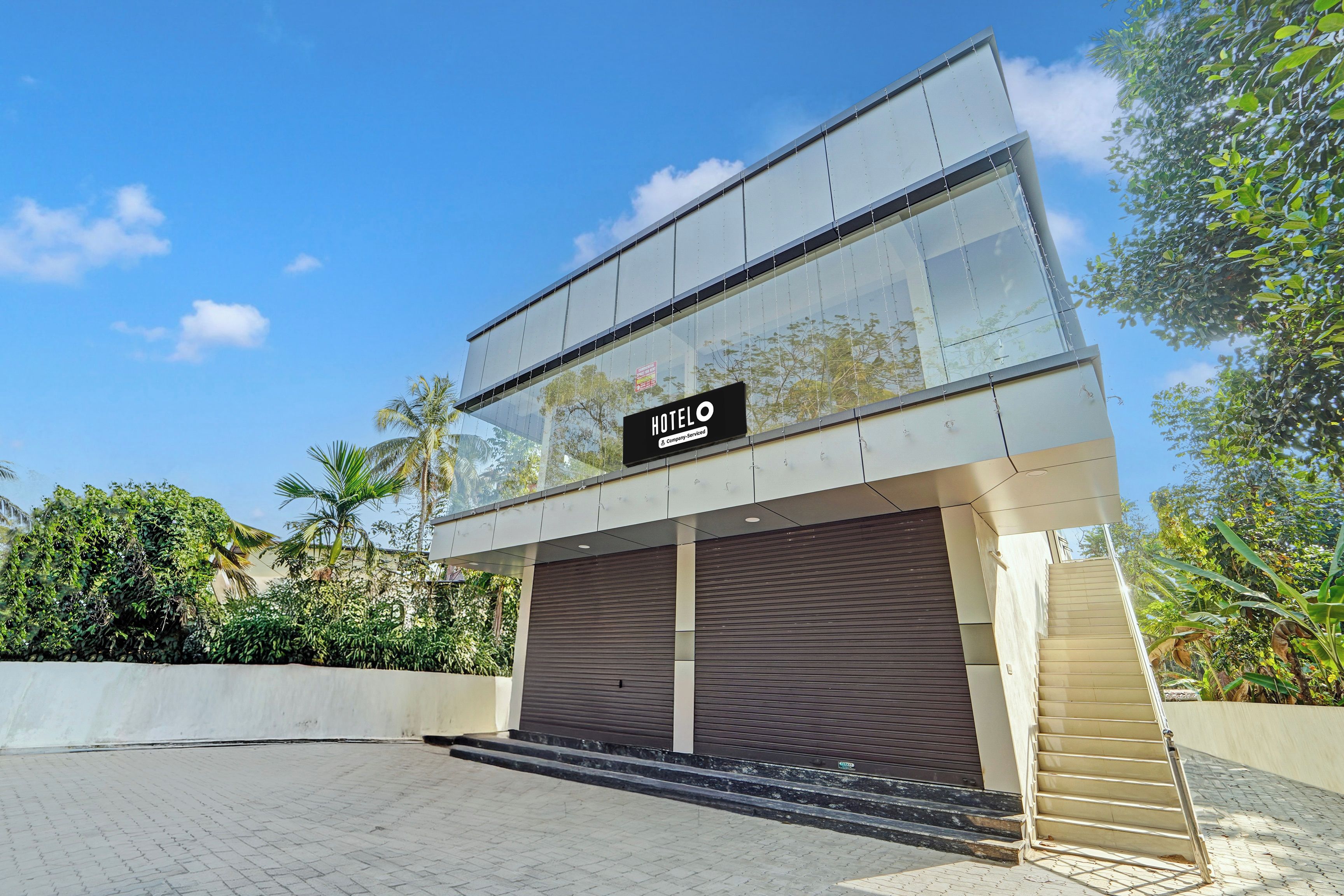 A modern hotel with a glass facade, a sign reading 'HOTEL', and a covered entrance.