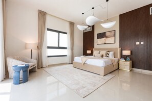 Ein modernes Schlafzimmer mit einem großen Bett, Nachttischen, einem Sessel und einem Fenster.