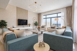 Ein modernes Wohnzimmer mit einem Flachbildfernseher, zwei Sofas, einem Couchtisch und einem großen Fenster mit Blick.