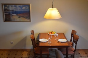 A dining area with a table set for two, a fruit bowl, and a hanging lamp. - Balmer See with direct lake view (Balm\/Usedom)