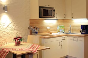 Una cocina compacta con microondas, pileta y una pequeña mesa con un florero.