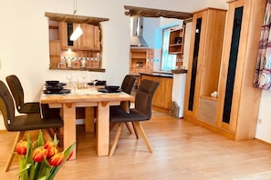 A dining area with a wooden table, chairs, and a vase of tulips. - Holiday apartment with 3 bedrooms (Schönau am Königssee)