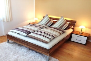 A bed with striped bedding, a wooden headboard, and two bedside tables with lamps. - Holiday apartment with 3 bedrooms (Schönau am Königssee)